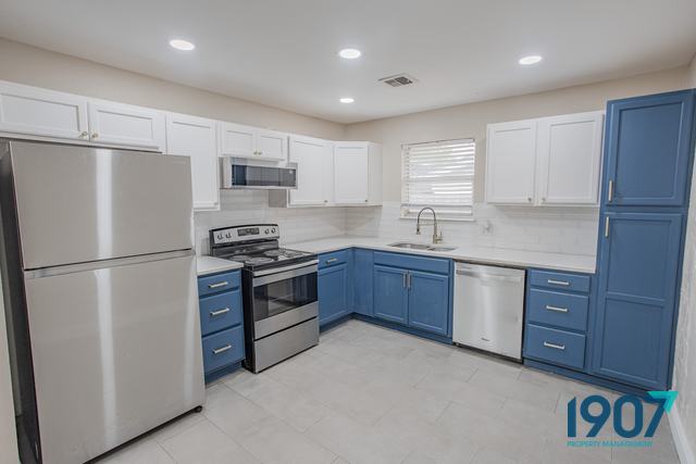 Two-tone kitchen with blue and white cabinets and stainless appliances