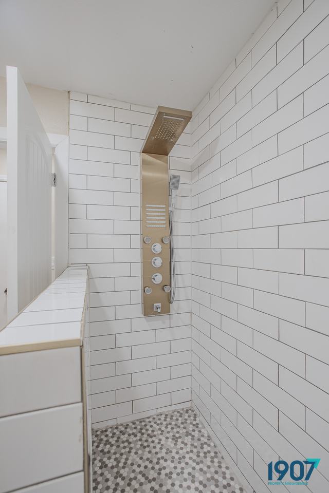 Walk-in shower with white subway tile and a rainfall shower panel