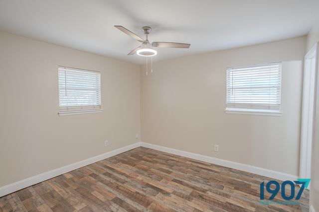Bedroom with wood-look plank flooring and two windows