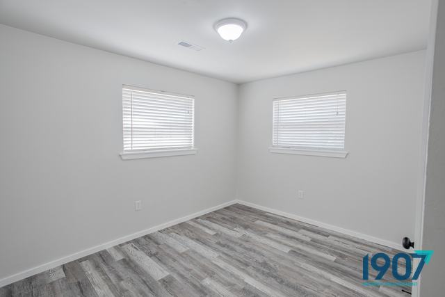 Bedroom with plank flooring and two windows