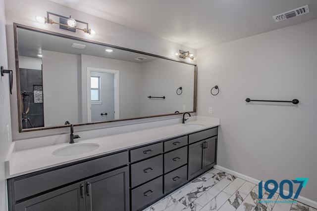 Double vanity with dark cabinets and a full-width mirror